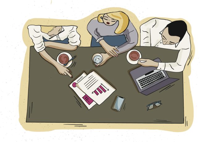 Persone al lavoro durante una riunione aziendale con documenti e computer